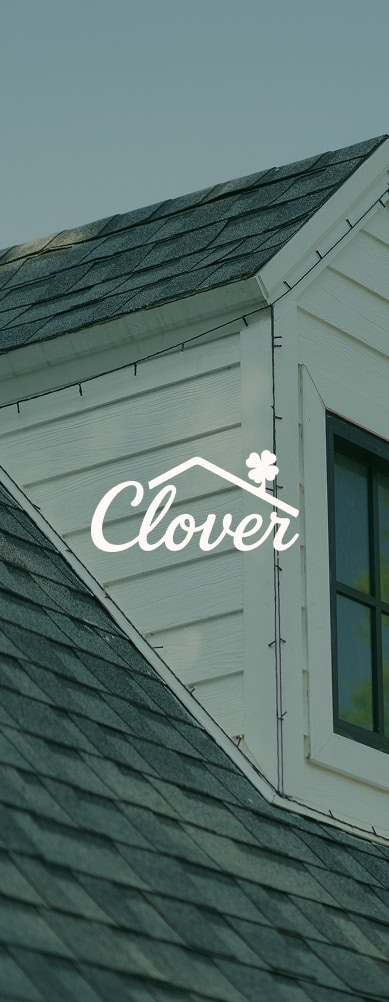 The image shows the roof and window of a house with gray shingles, featuring the words "Clover Roofing" and a clover leaf graphic overlayed in the center, highlighting quality roofing in South Carolina.