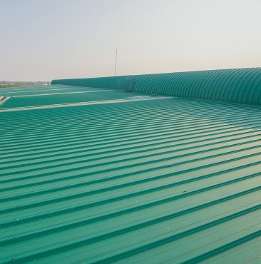 Large green corrugated metal roof with ridges, seen under a clear South Carolina sky—a signature project by Clover Roofing.