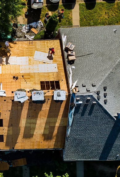 Aerial view of a house with part of the roof removed and Clover Roofing workers installing new materials on the exposed wooden structure in South Carolina.